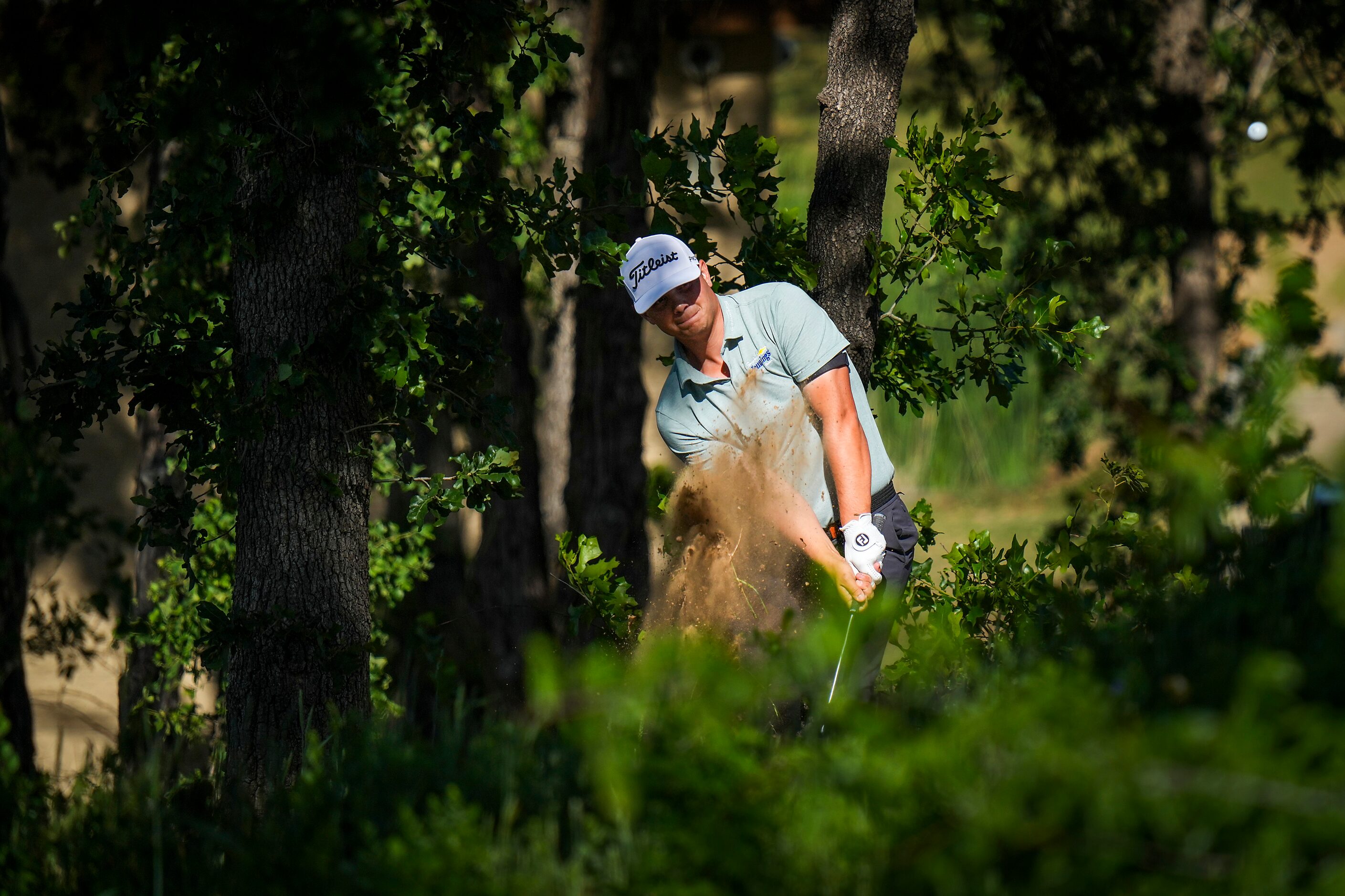 John VanDerLaan hits a shot from a wooded area on the 18th hole during the final round of...