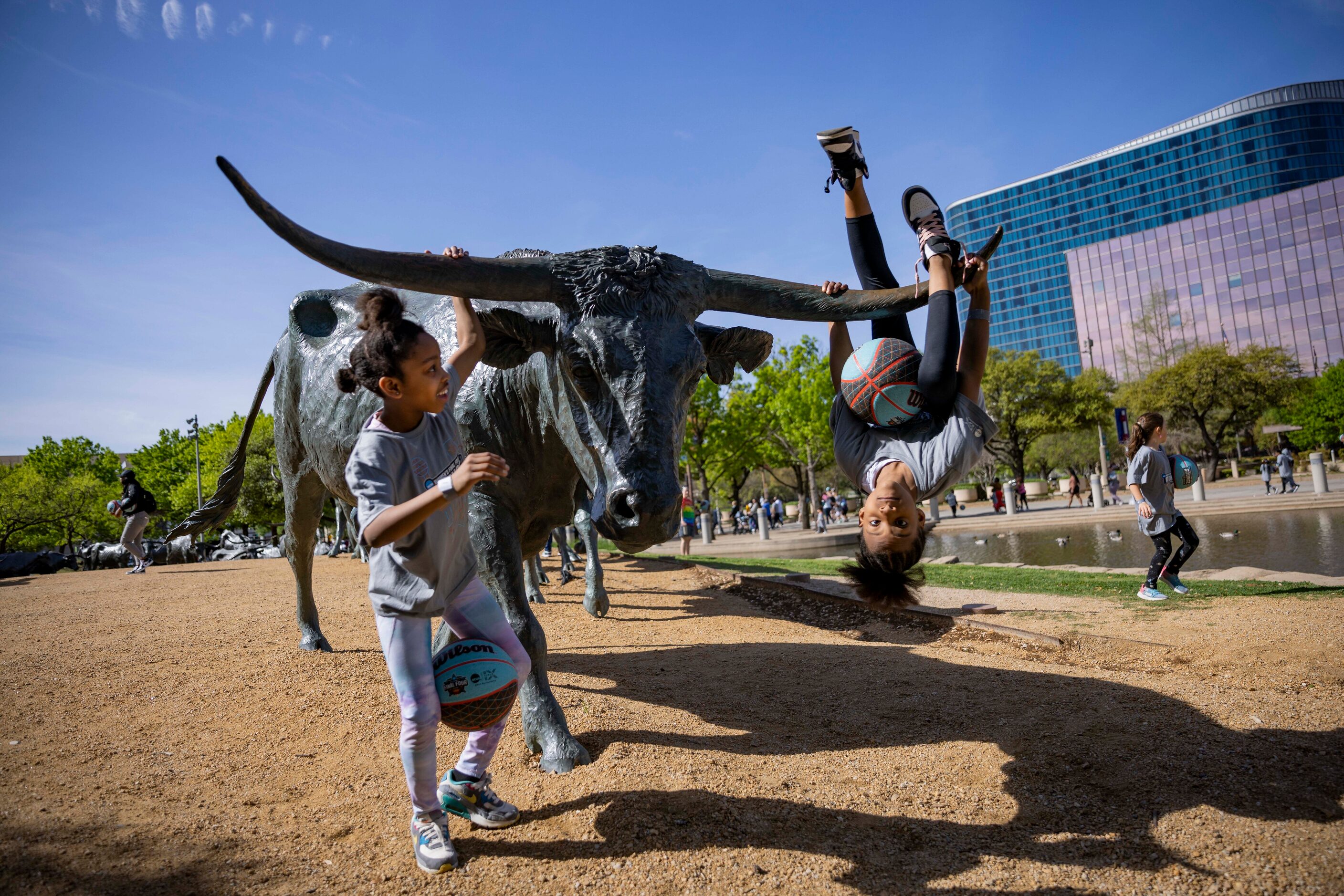 Best friends Kamea Venson, 10, and Delecia Sims, 9, of Fort Worth play on a cattle statue at...