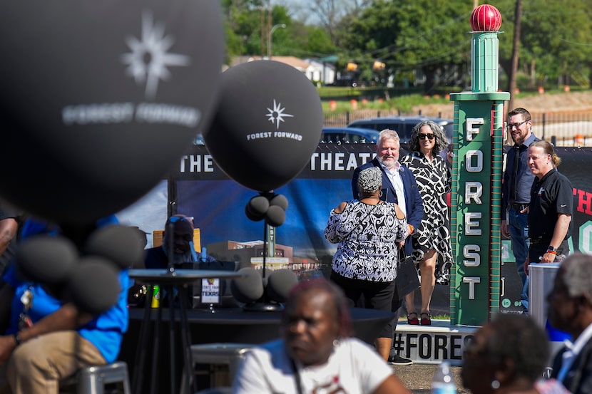 Guests pose for a photo with a replica of the theater’s tower during a groundbreaking...