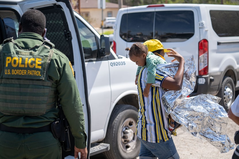 Migrants wait to board a bus to Houston at a humanitarian center after they were released by...