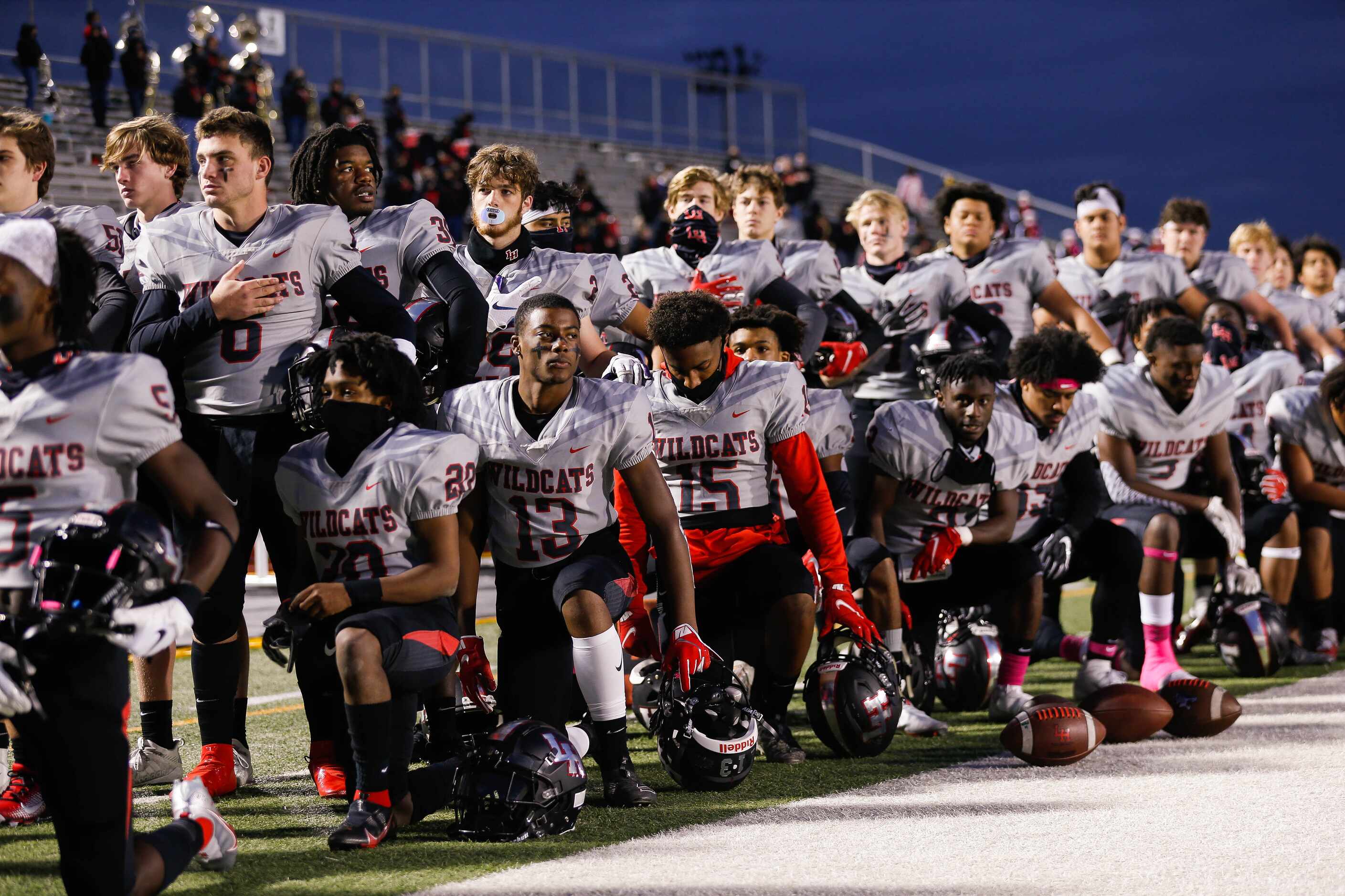 Lake Highlands players kneel and stand during the national anthem before a football game...