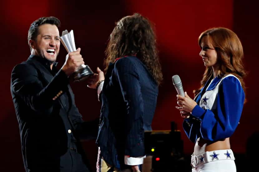 Luke Bryan (left) receives his Entertainer of the Year award from Steven Tyler during the...