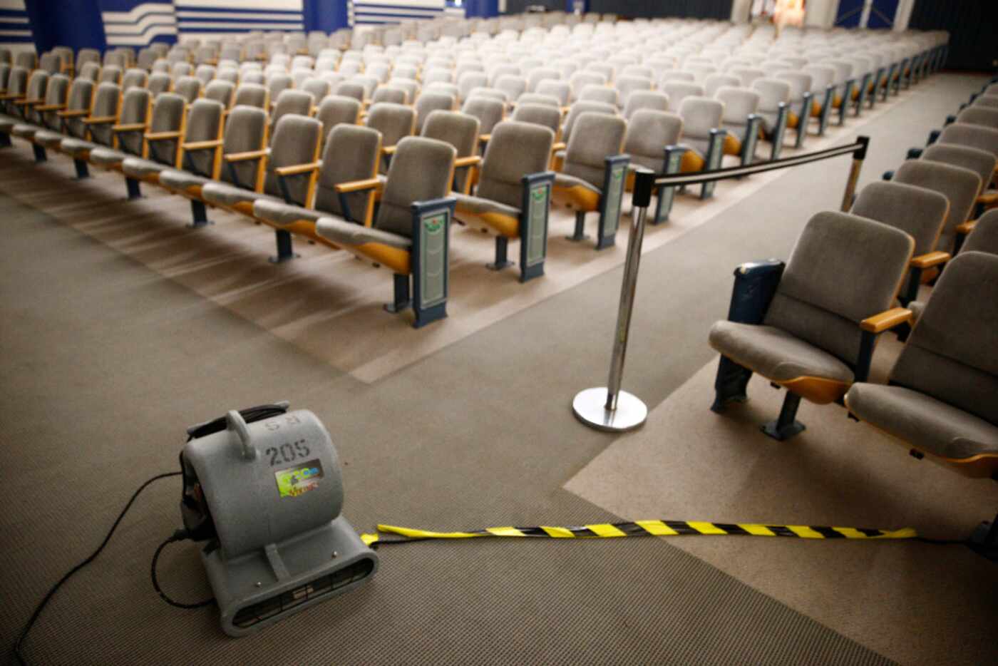An electric fan dries the carpet after water flooded the Margaret & Al Hill Lecture Hall in...