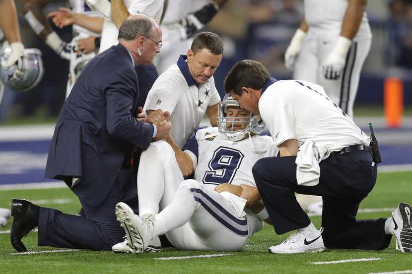 Dallas Cowboys quarterback Tony Romo (9) is helped off the field by team staff after...