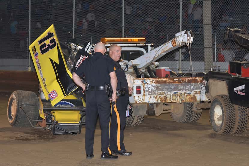 In this Wednesday June 12, 2013 photo, police stand near the wreckage of the race car that...