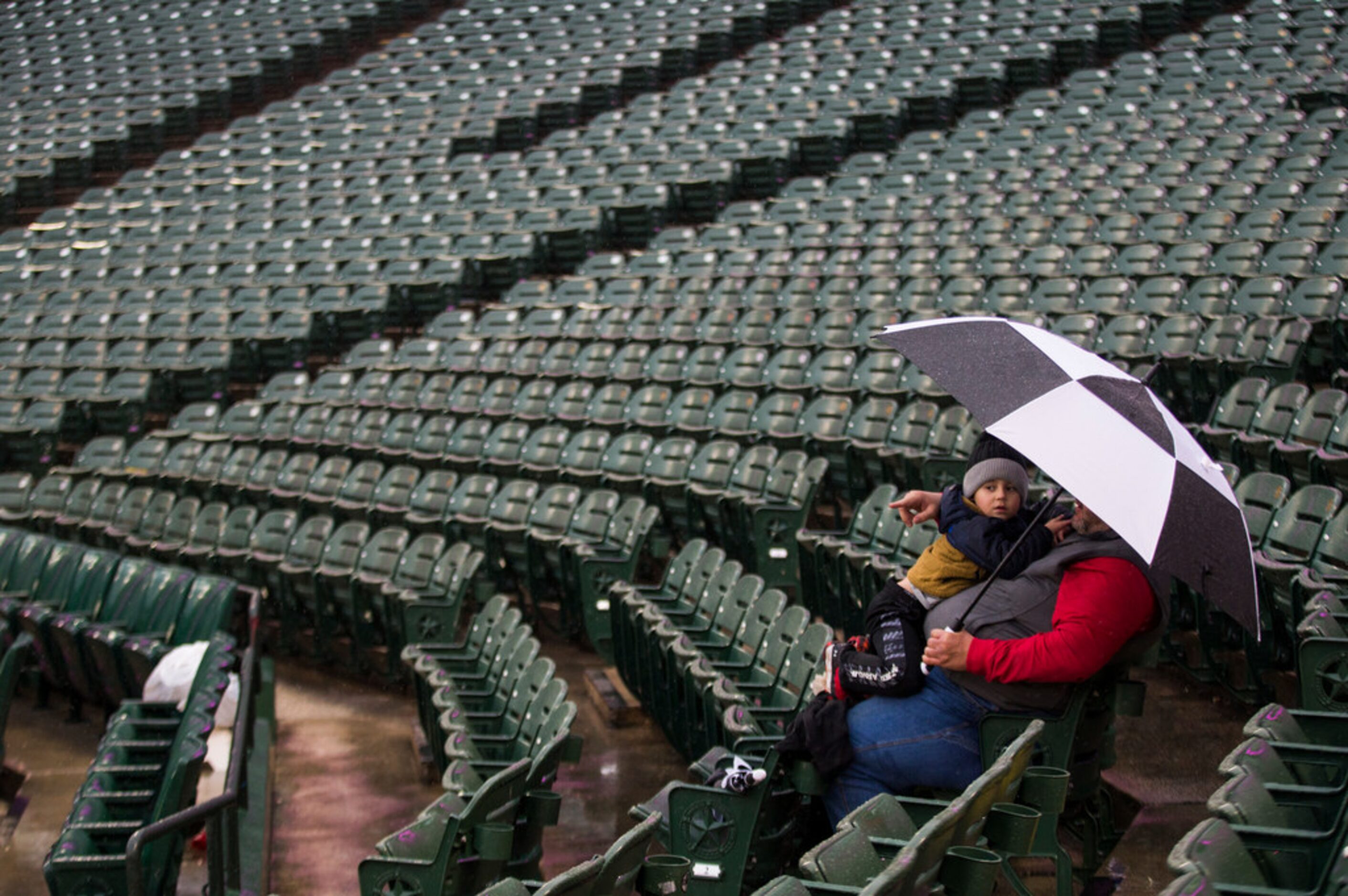 Chris Dickson and his grandson wait in the rain before an MLB game between the Texas Rangers...