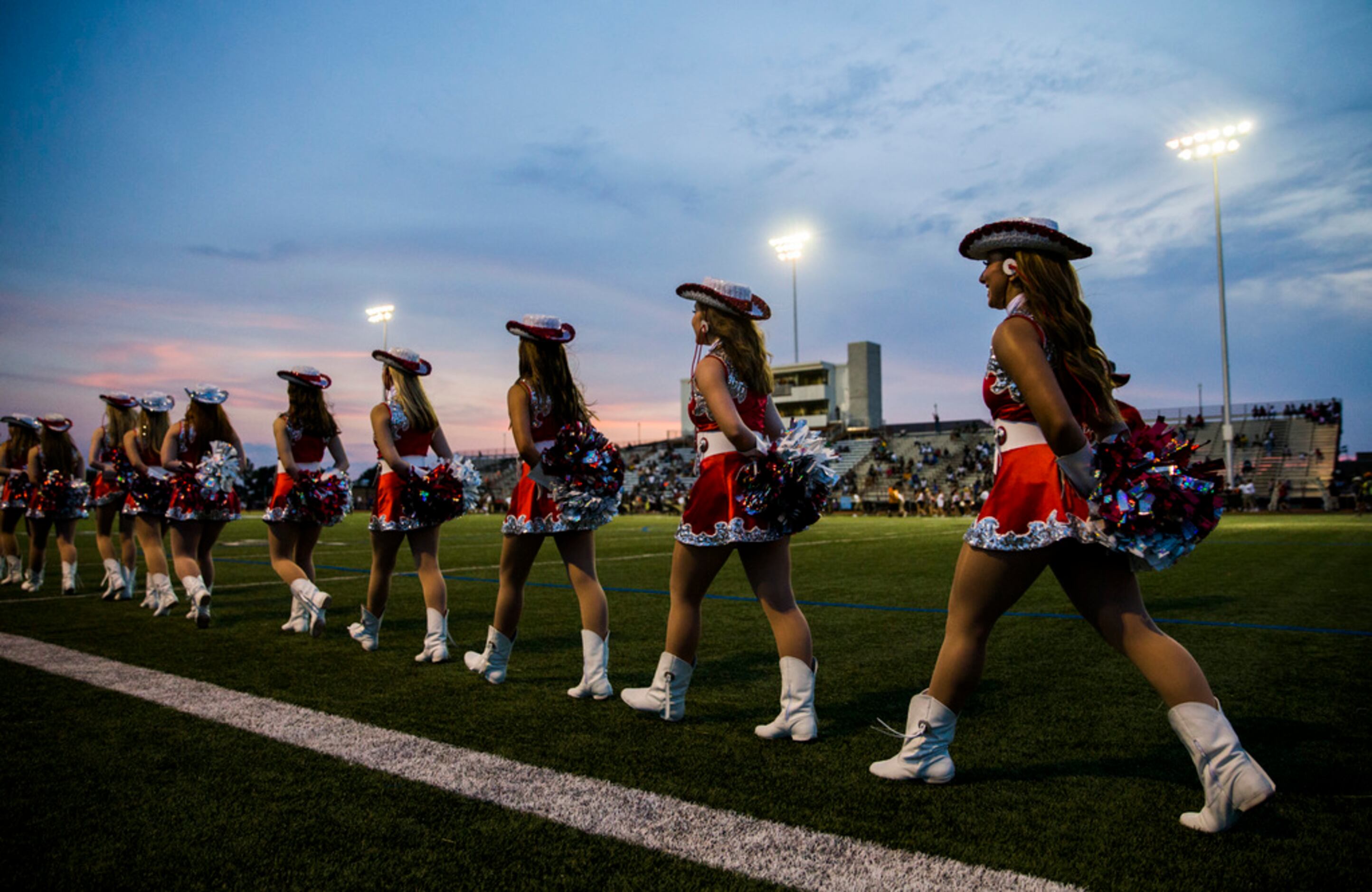Flower Mound Marcus dance team members enter the field to perform at half time of a high...