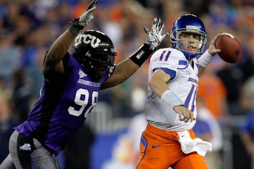 Kellen Moore #11 of the Boise State Broncos passes the ball as he is hit by Jerry Hughes #98...