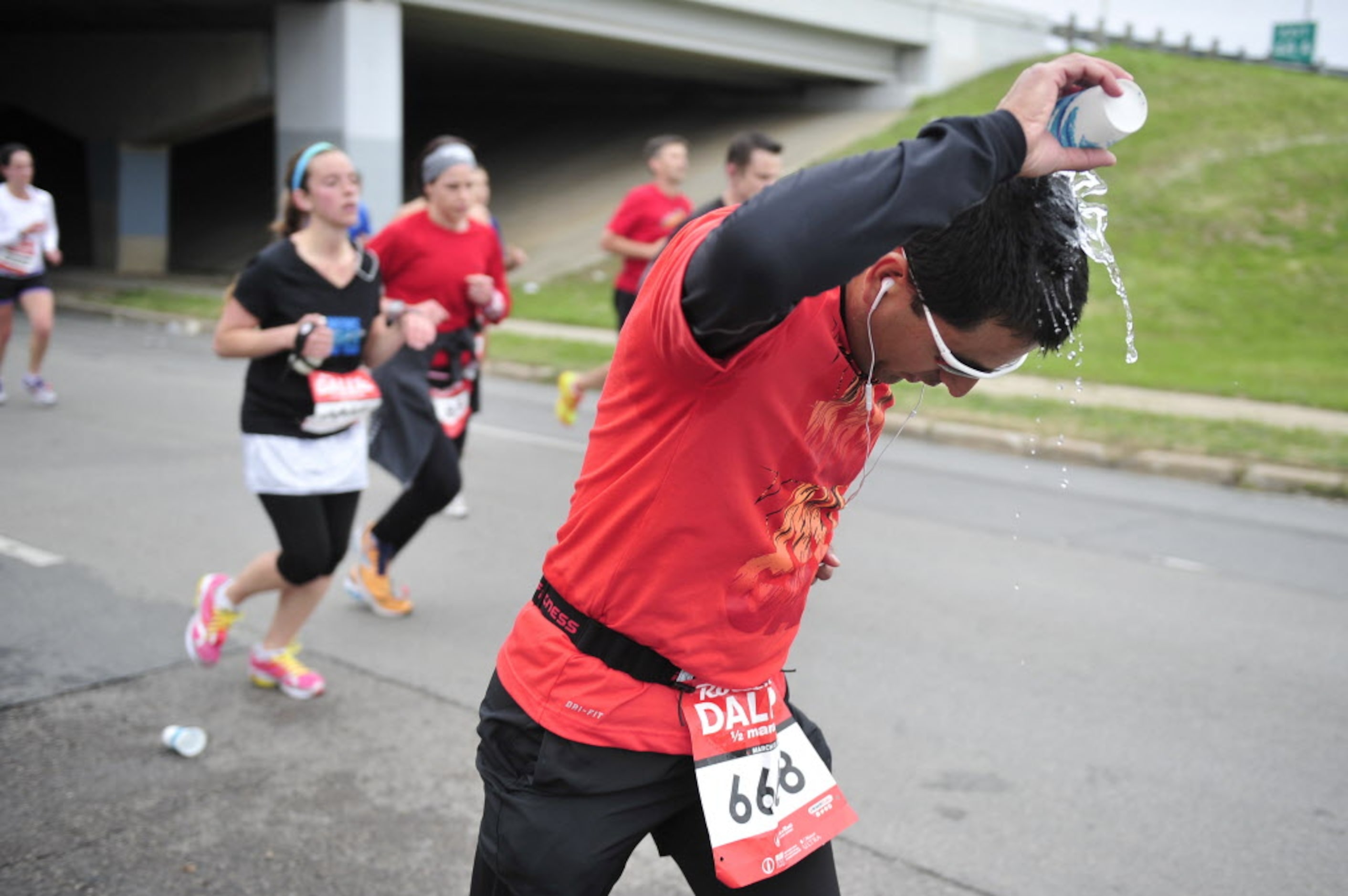 A runner douses himself with water at a water station during the Dallas Rock N' Roll...