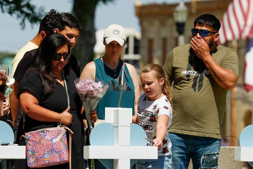 Khloie Torres, 10, grabs a marker to sign a cross for a victim of the Robb Elementary School...