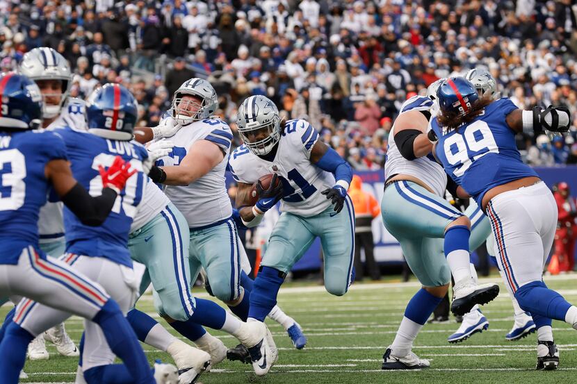 Dallas Cowboys running back Ezekiel Elliott (21) breaks through the line on his way to a...