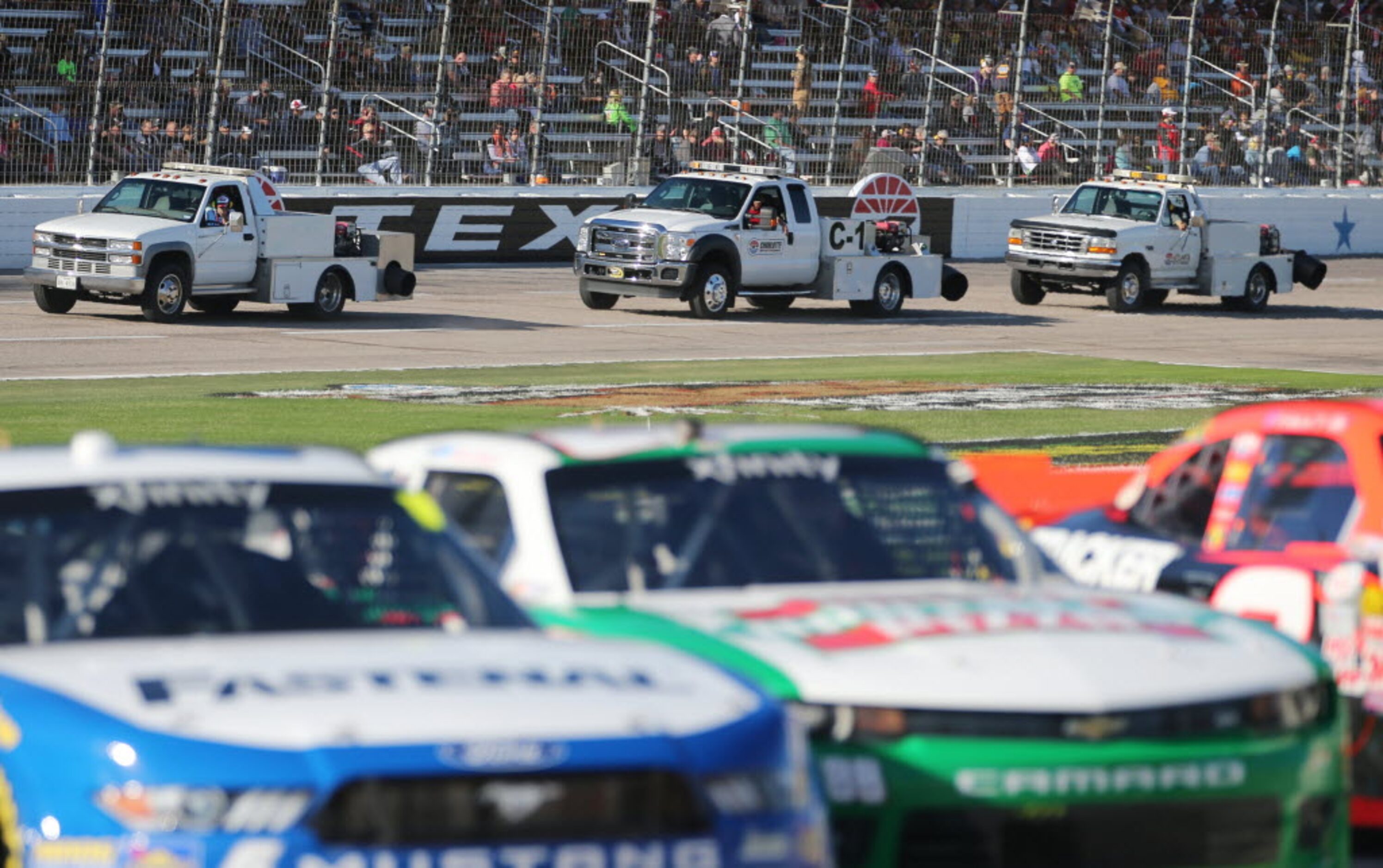 A group of trucks equipped with blowers make a lap around the track before the start of the...