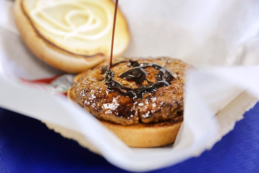 Kaiho tops a burger with teriyaki sauce at his new Japanese burger restaurant Ookuma.