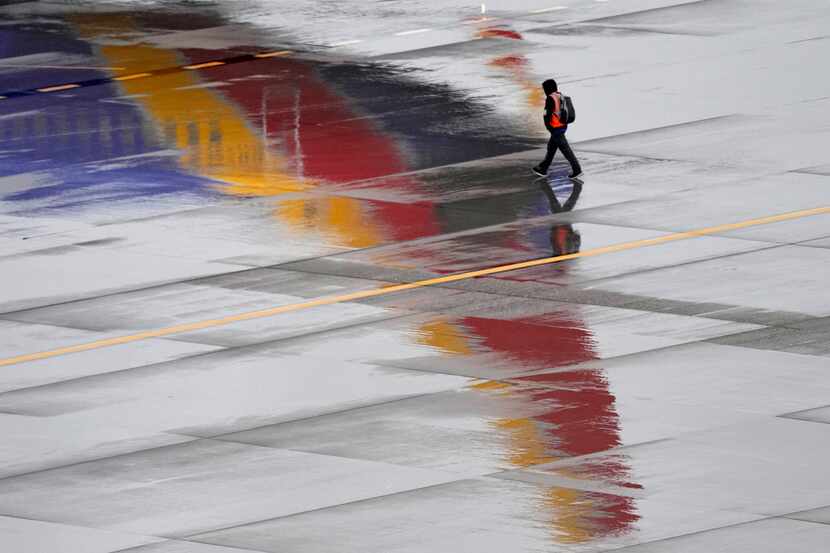FILE - A ground operations crew member walks past a Southwest Airlines jet sitting at a...