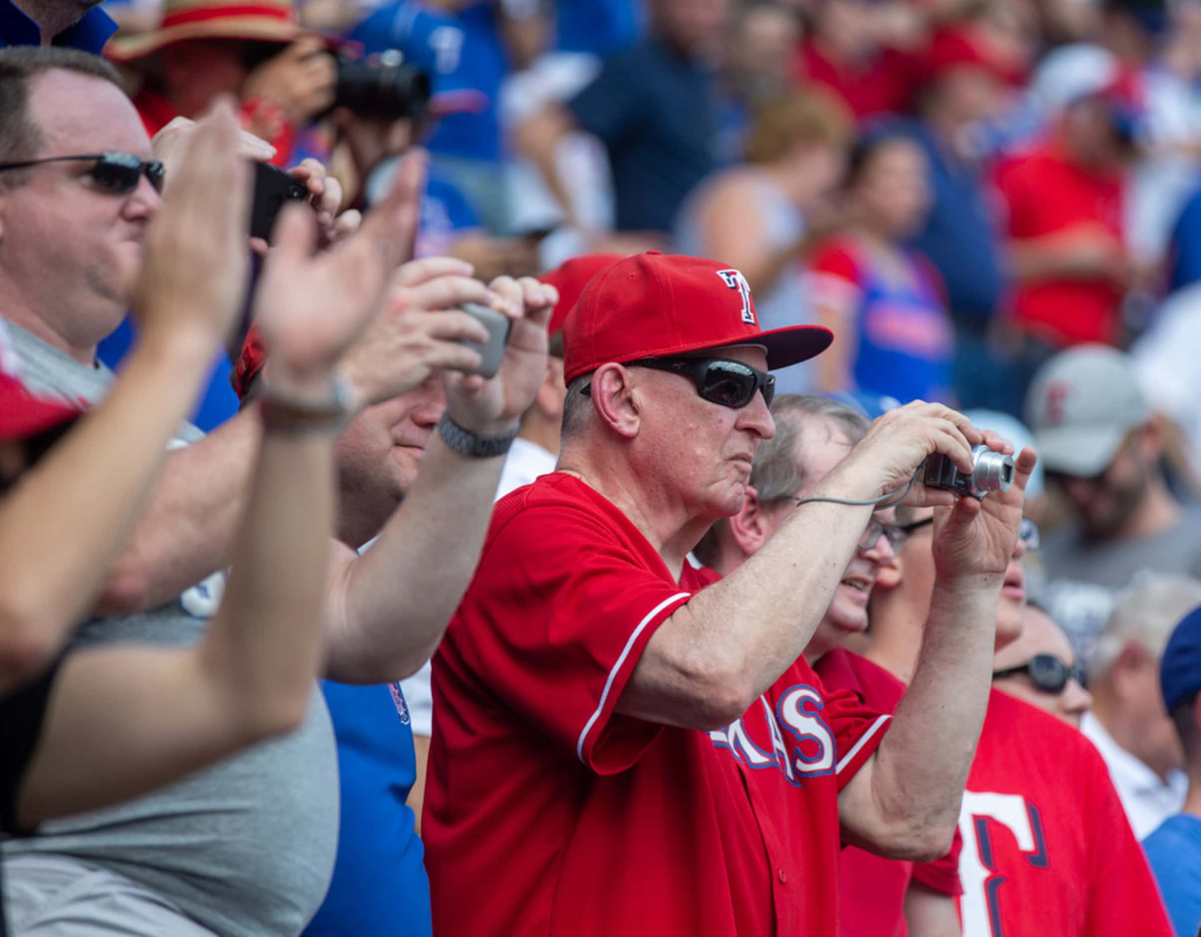 Fans cheer as Texas Rangers legend Nolan Ryan pitches the final first pitch for the Rangers'...