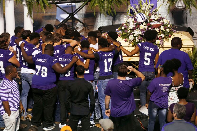 Newton High School football team talk to each other after a memorial service for Newton High...