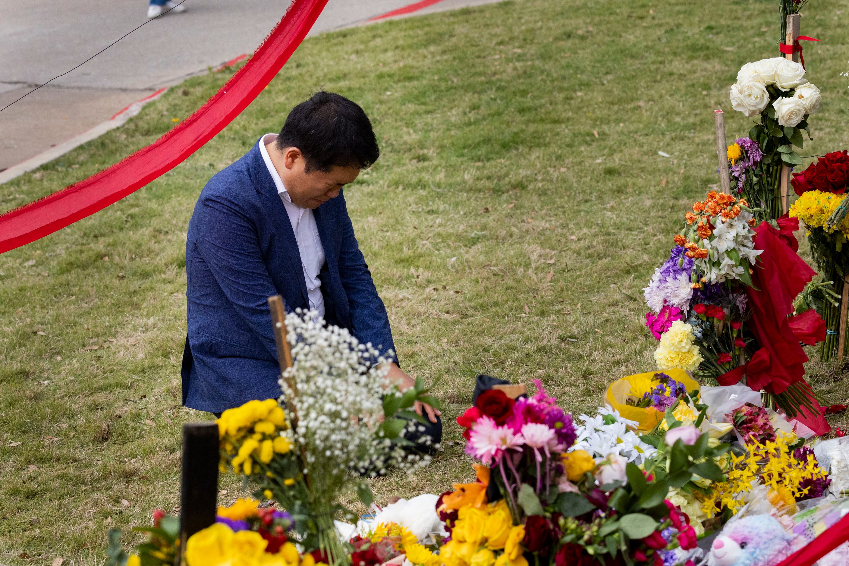 A man kneels at the memorial outside the mall honoring the victims of a mass shooting at...