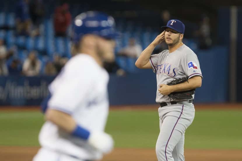 Texas Rangers pitcher Shawn Tolleson, right, looks on as he walks Toronto Blue Jays Josh...
