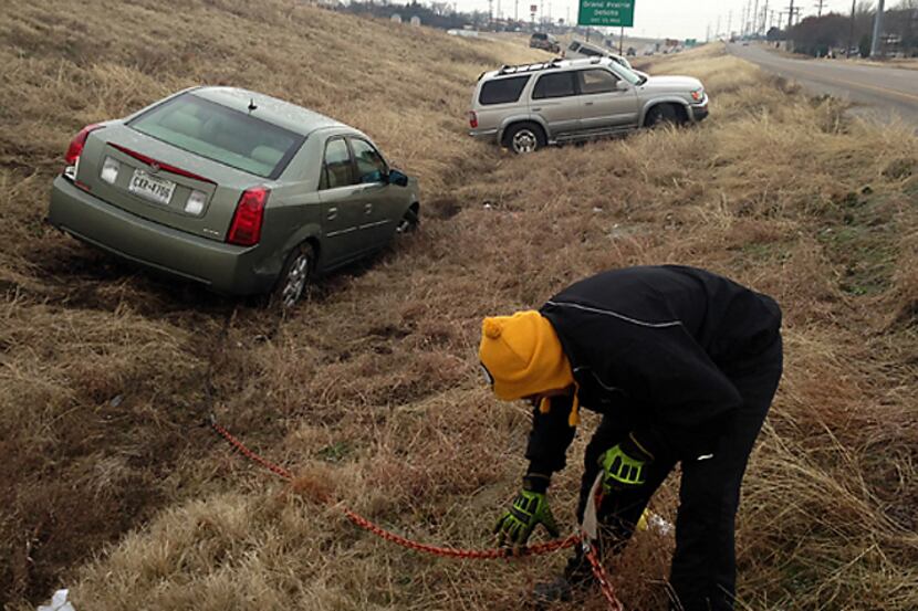 Mark Leismer connects a tow chain to a friend's car that slid off Highway 67 Tuesday morning...