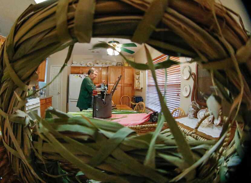 A wreath made of cattail reeds frames Mike Turrentine as he reweaves a child's rocking chair...