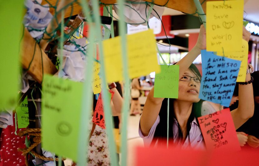 A woman hangs a message card for passengers aboard a missing Malaysia Airlines plane, at a...