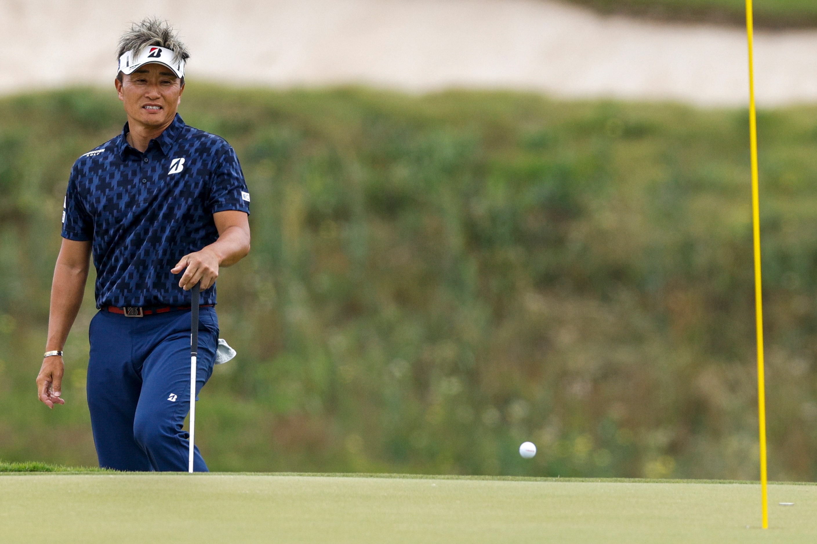 Katsumasa Miyamoto of Japan watches as his chip shot bounces on the eighth green during the...