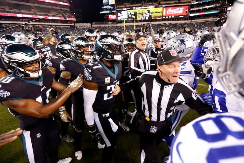 A referee tries to separate the Dallas Cowboys and Philadelphia Eagles players after they...