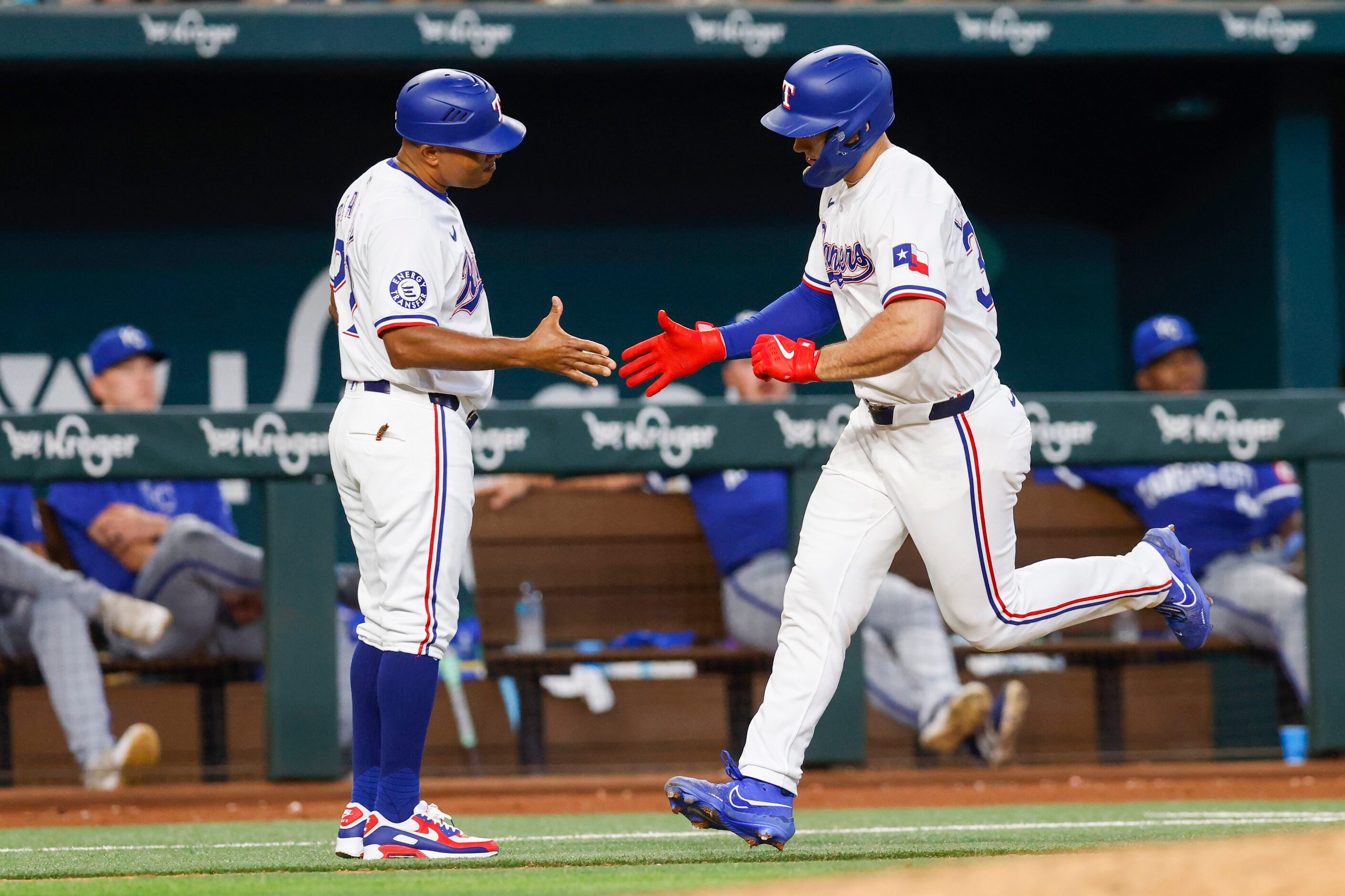 Texas Rangers left fielder Wyatt Langford (36) high-fives third base coach Tony Beasley (27)...