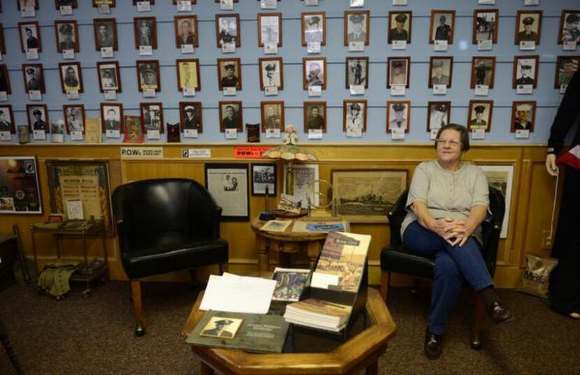 
 Docent Deloris Ballard sits among the "wall of honor" featuring Royse City service members...