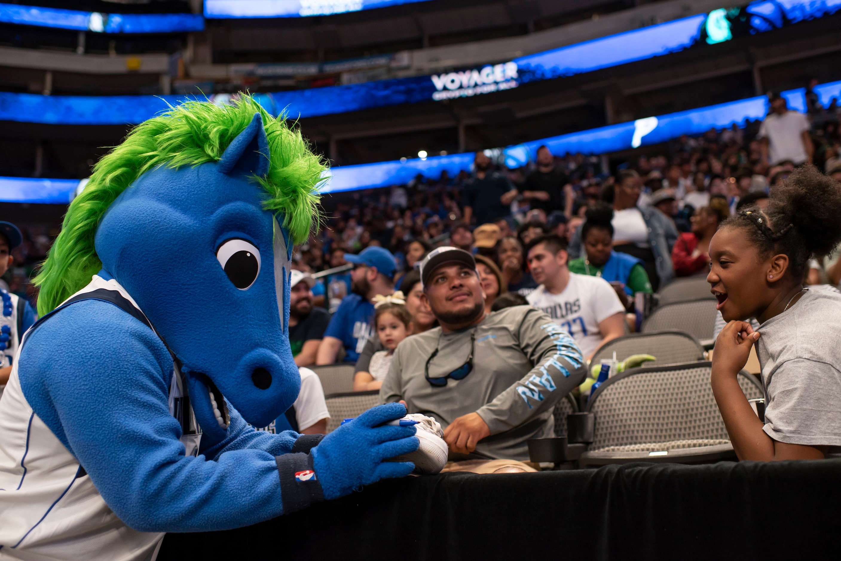 Champ, the Mavs mascot, signs a shoe for a fan during the Dallas Mavericks official watch...