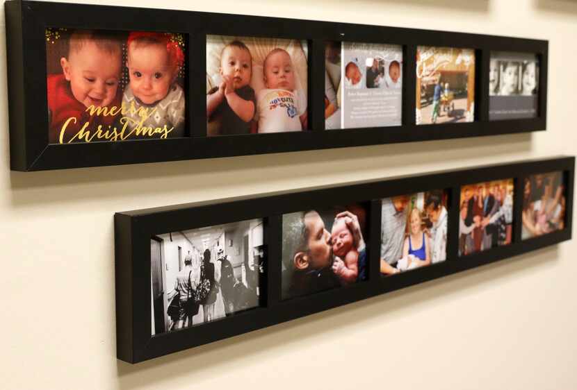 Photos from families who had a child carried by a surrogate are displayed on the office...