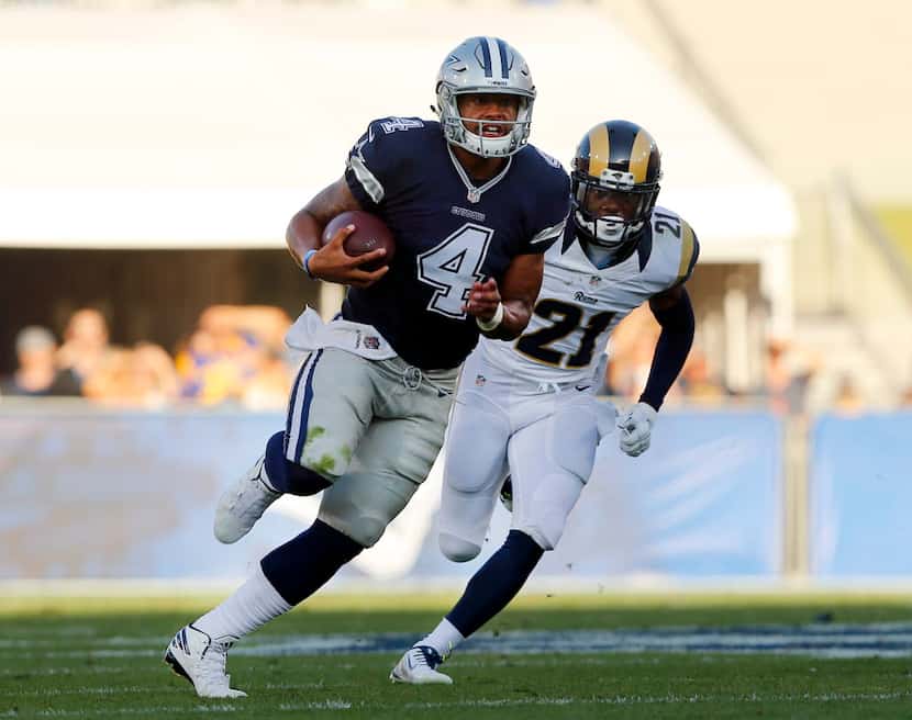 Dallas Cowboys quarterback Dak Prescott (4) keeps the ball and rushes past Los Angeles Rams...