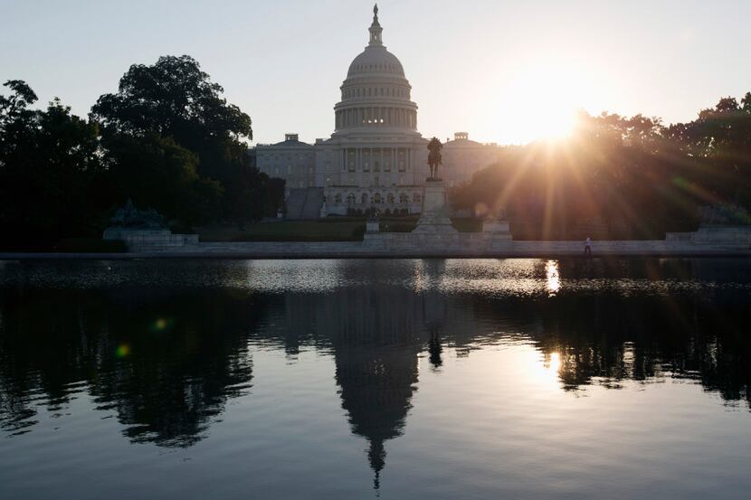 The Capitol building reflected in the Capitol Reflecting Pool at sunrise in Washington. 