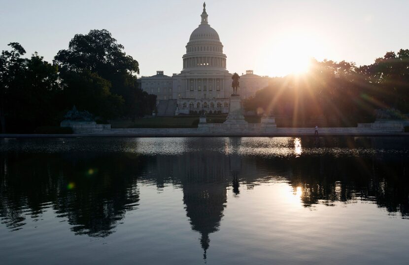 The Capitol building reflected in the Capitol Reflecting Pool at sunrise in Washington. 