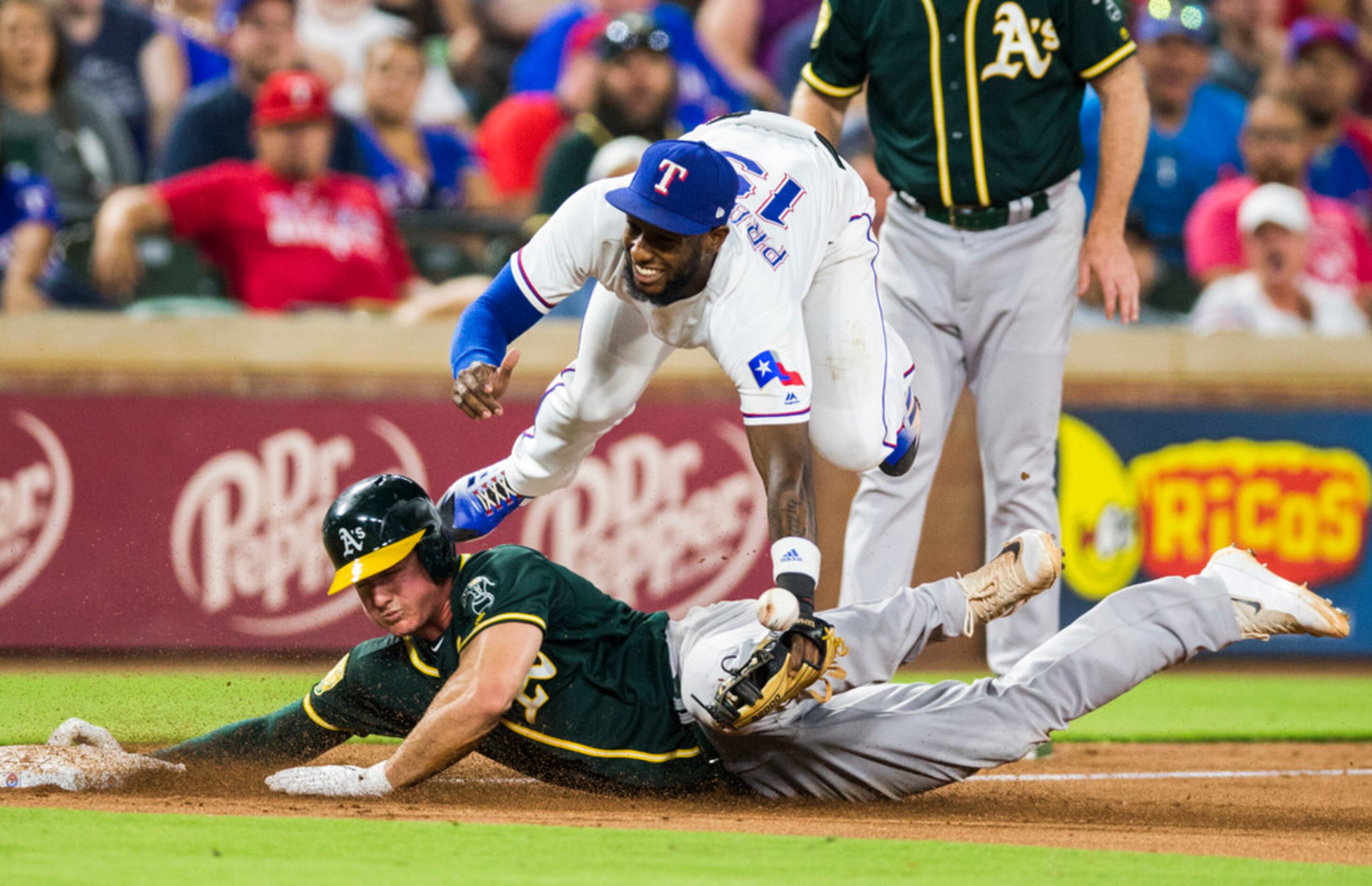 Texas Rangers third baseman Jurickson Profar (19) is tripped up by Oakland Athletics third...