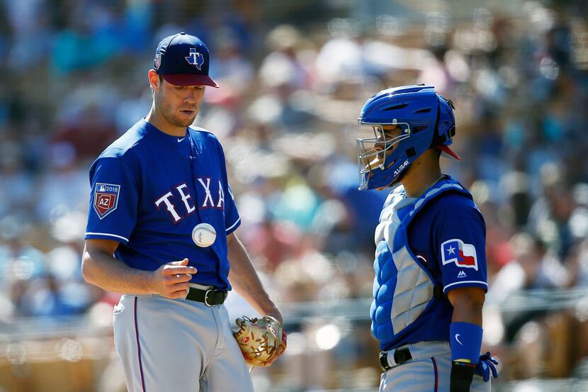 Texas Rangers starting pitcher Doug Fister, left, flips the ball in the air as he get a...