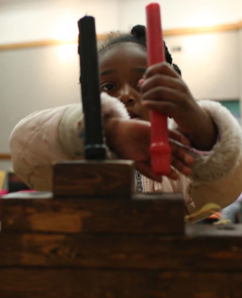 Lillian Pryor, 5, puts the second candle in during Wednesday's Kwanzaa celebration at the...