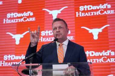 Jim Schlossnagle flashes a hook'em sign as he speaks at a news conference after he was...