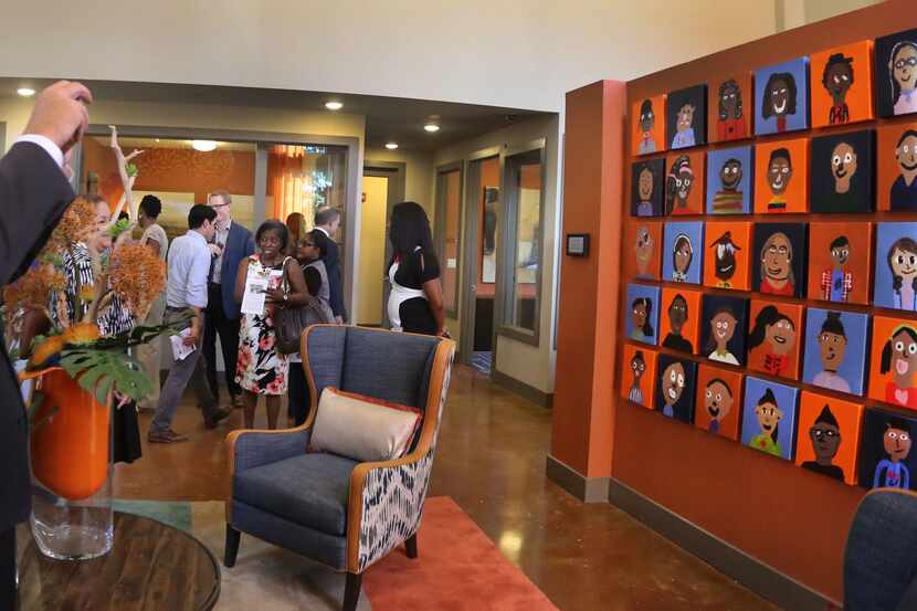Dallas Mayor Mike Rawlings takes a smartphone photo of a wall of hand-painted portraits of...