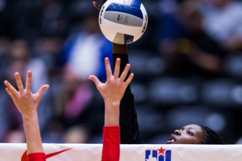Hebron's Adanna Rollins (1) spikes the ball past The Woodlands' Ally Haden (2) during the...
