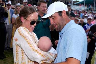 Meredith Scheffler, left, hands husband Scottie Scheffler, right, their baby Bennett...