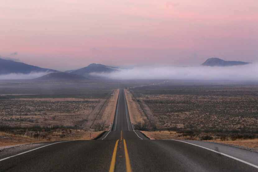 This file photo shows a pink sky and low-lying clouds on a highway just east of Alpine in...