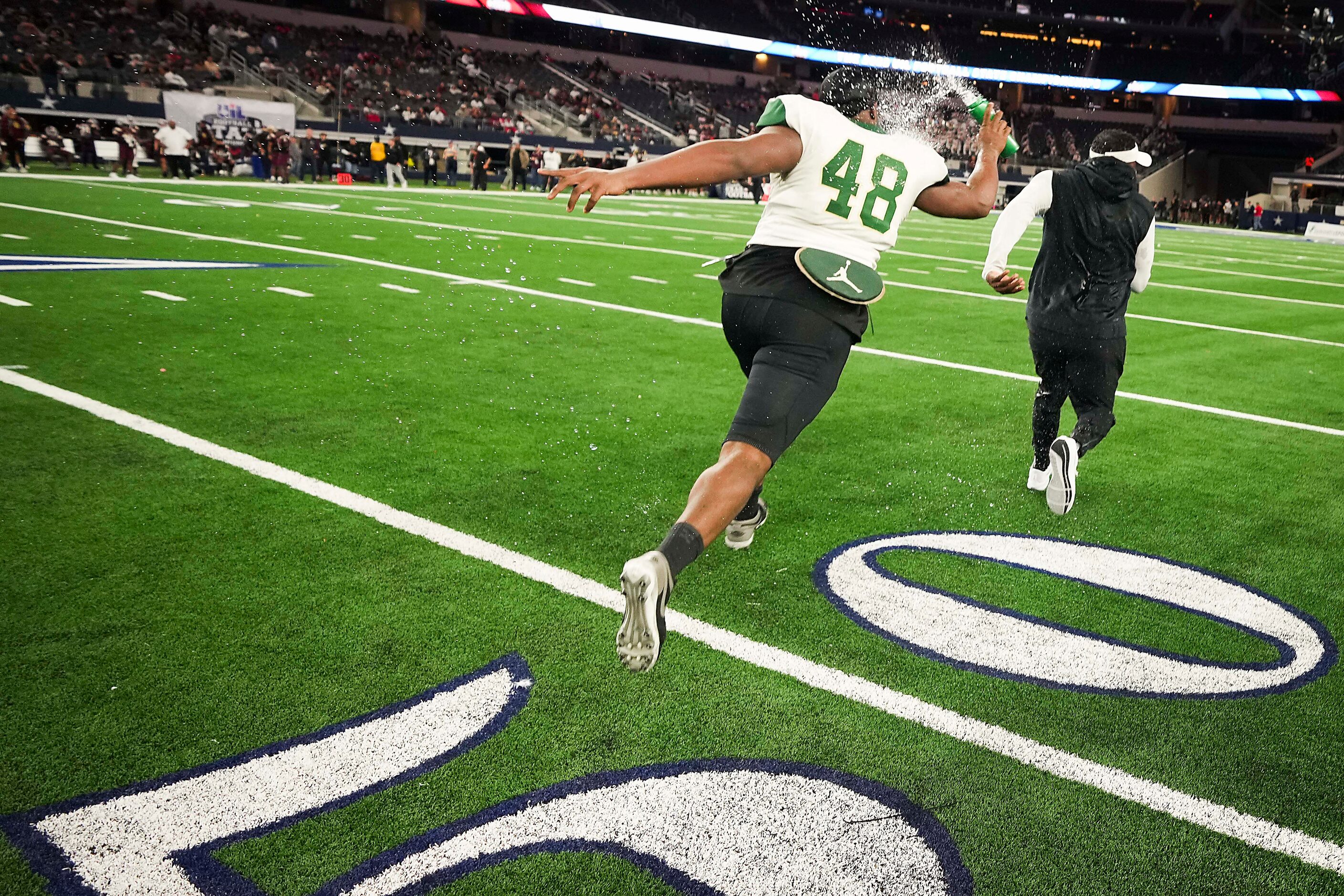 DeSoto defensive lineman Jason Douglas (48) chases head coach Claude Mathis with a bottle of...