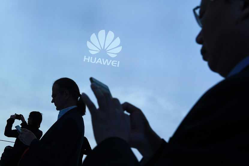 Visitors use their mobile phone at the Huawei stand on the second day of the Mobile World...