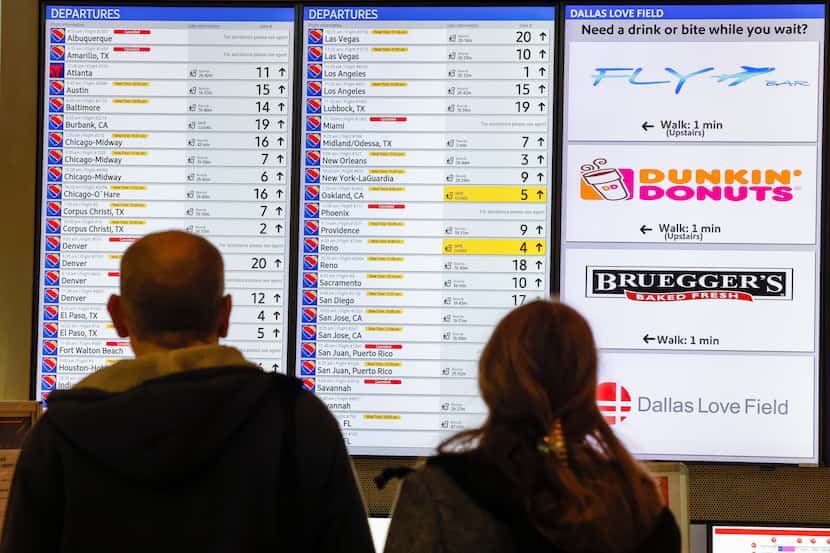 Damon Parker (left) and Madelyn Parker stop to look at a departure board for their flight to...
