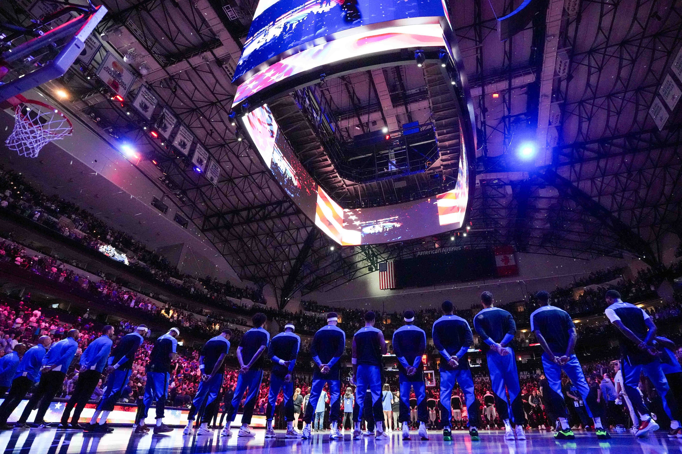 Dallas Mavericks players stand for the national anthem before an NBA basketball game against...