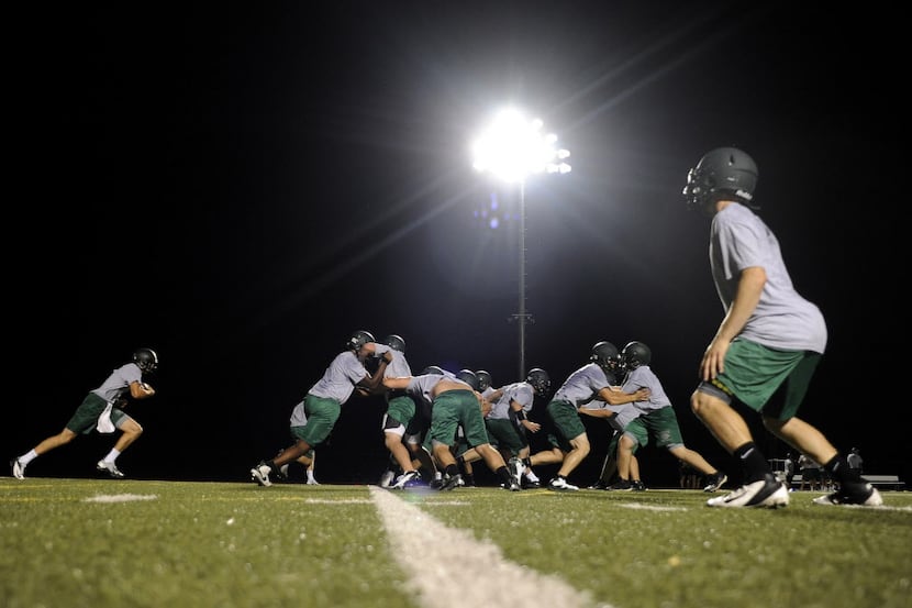 Prosper High School players go through drills just before 2:00 a.m. during their first...