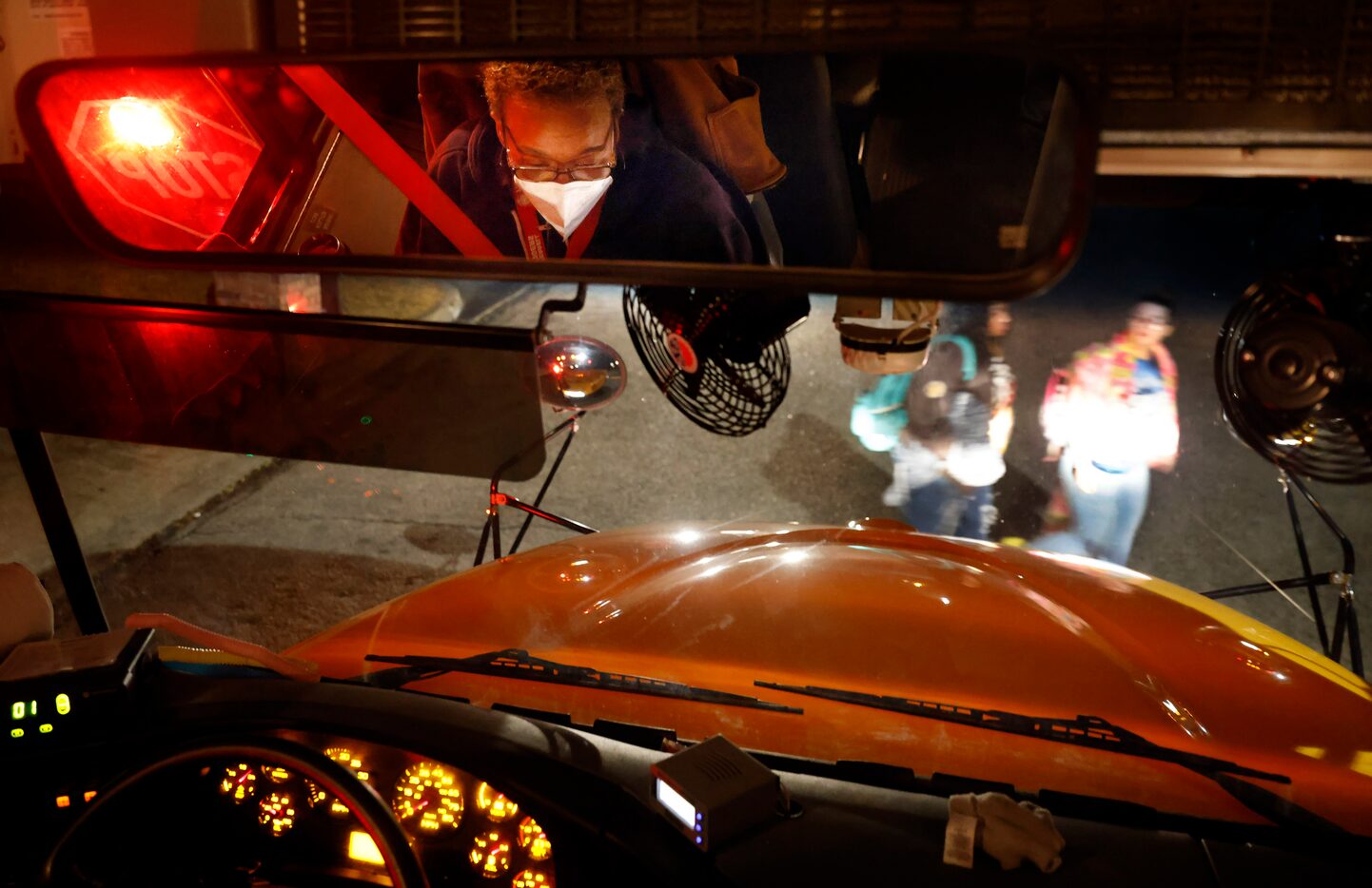 Bus driver Schrildea Glover (reflected in mirror) picks up students in the predawn hour...