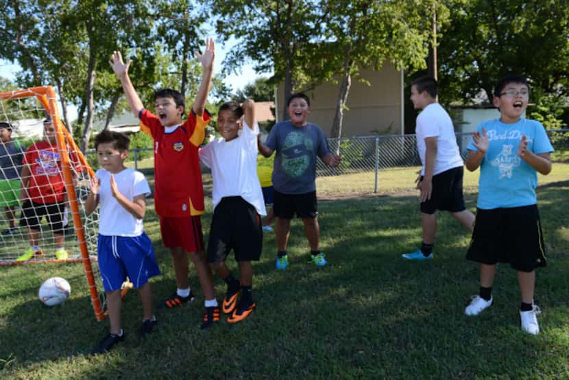 Fourth and fifth grade soccer players react after a teammate scores a goal during the team's...
