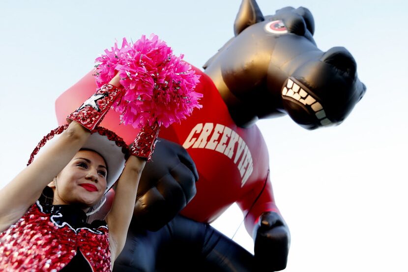 A Creekview drill team member rallies fans before a high school football game against...